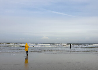 People walking by the sea under cloudy sky