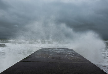 wave splash against concrete groyne during yellow weather warning in brighton, england