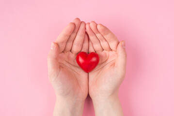 St. Valentine's day celebration concept. Top above overhead pov first person view photo of female hands holding a red heart isoalted on pink pastel background with copyspace