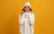 © mary_markevich - young smiling happy pretty blond woman wearing white knitted sweater, scarf and hat, warm winter cold season fashion accessories trend, posing on yellow studio background isolated