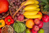 Fototapeta Kuchnia - Group vegetables and Fruits Apples, grapes, oranges, and bananas in the wooden basket with carrots, tomatoes, guava, chili, eggplant, and salad on the table.Healthy food concept