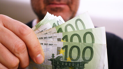 100 euro banknotes in the hand of an unrecognizable rich man