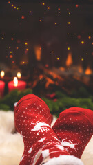 Red knitted socks against the background of New Year's decorations and fireplace, Christmas tree garland. Cozy winter evening by the fireplace, blurred background. New Year and Christmas festive backg