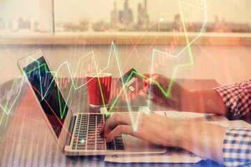 Double exposure of man hands holding a credit card and Forex graph drawing. Stock trading and digital fintech in Internet E-commerce concept.