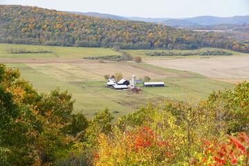 the distance view of a farm surrounded by striking color of fall foliage near wyalusing, pennsylvani