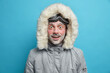 © wayhome.studio  - Emotional shocked cheerful man wears winter jacket has red face covered with ice cannot believe in astounding news isolated over blue background. Male snowboarder recreats during cold season