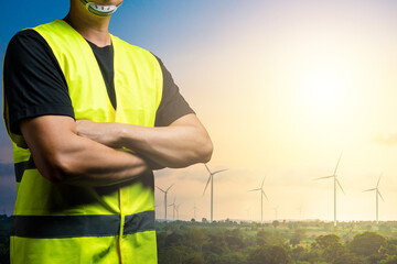 Wall Mural - Green energy concept : Maintenance technician wear reflective shirts over black clothes. There is a background in a field of wind turbines for generating electricity.