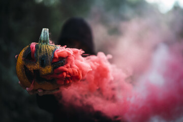 Canvas Print - Man holding a carved pumpkin with red smoke - the concept of Halloween