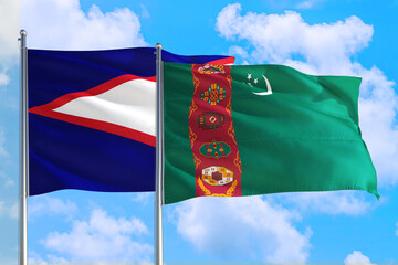 Wall Mural - Turkmenistan and American Samoa national flag waving in the windy deep blue sky. Diplomacy and international relations concept.