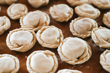 Wall Mural - pile of small homemade uncooked dumplings with meat on kitchen table. national traditional Russian cuisine. do it yourself. top view, flat lay