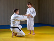 © marritch - Black belt judoka helps young female yellow belt judoka to tie a belt