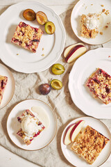 Sticker - Top view of delicious plum cakes with crumbles and ice cream on plates on a white table