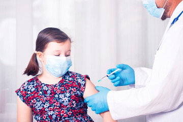 Vaccination concept. Male doctor vaccinating cute little girl in clinic.