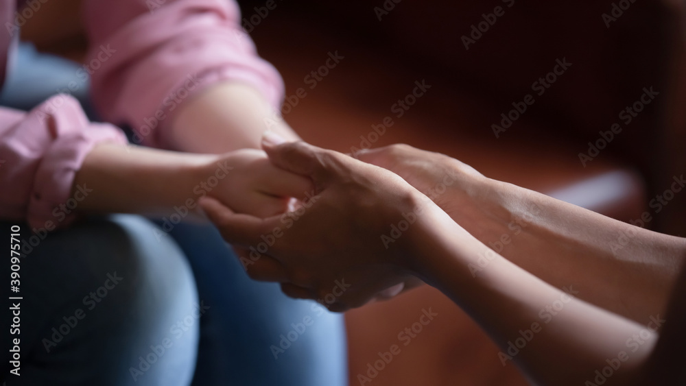 Professional assistance. Close up of biracial female psychologist therapist hands holding palms of millennial woman or teenage girl patient client talking consulting helping accept difficult situation - obrazy, fototapety, plakaty 