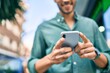 © Krakenimages.com - Young latin man smiling happy using smartphone walking at the city.