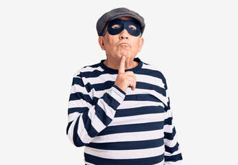 Canvas Print - Senior handsome man wearing burglar mask and t-shirt thinking concentrated about doubt with finger on chin and looking up wondering