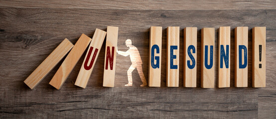 Pieces of wood with the german words for Healthy and Unhealthy - gesund und ungesund on wooden background