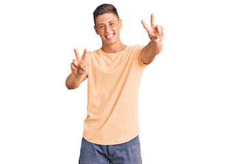 Poster - Young handsome man wearing casual clothes smiling with tongue out showing fingers of both hands doing victory sign. number two.