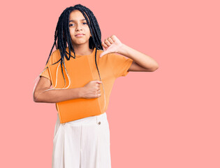 Poster - Cute african american girl holding notebook with angry face, negative sign showing dislike with thumbs down, rejection concept