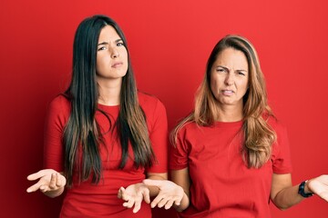 Sticker - Hispanic family of mother and daughter wearing casual clothes over red background clueless and confused with open arms, no idea concept.