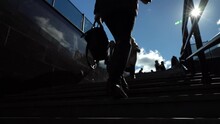 Slow Motion. Legs Of A Young Woman In Boots Climbing The Stairs From The Subway Up Against The Background Of A Clear Blue Sky On A Sunny Day.