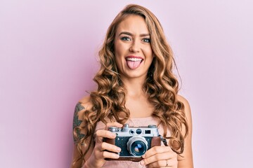 Poster - young blonde girl holding vintage camera sticking tongue out happy with funny expression.