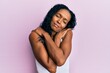 © Krakenimages.com - Middle age african american woman wearing casual clothes hugging oneself happy and positive, smiling confident. self love and self care
