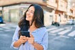 © Krakenimages.com - Young hispanic businesswoman smiling happy using smartphone at the city.