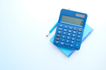 Close up of blue calculator and notepad on color background 
