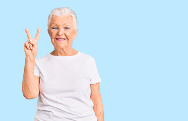 Senior beautiful woman with blue eyes and grey hair wearing casual white tshirt showing and pointing up with fingers number two while smiling confident and happy.