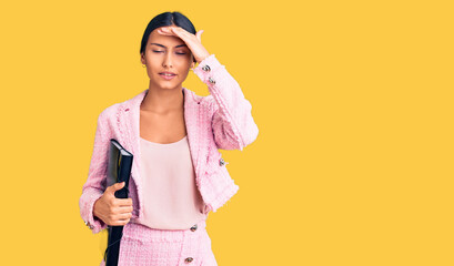 Poster - Young beautiful latin girl wearing business clothes holding binder stressed and frustrated with hand on head, surprised and angry face