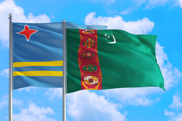 Wall Mural - Turkmenistan and Aruba national flag waving in the windy deep blue sky. Diplomacy and international relations concept.