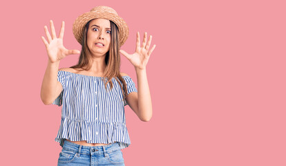 Young beautiful girl wearing hat and t shirt afraid and terrified with fear expression stop gesture with hands, shouting in shock. panic concept.