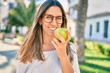 © Krakenimages.com - Young caucasian woman smiling happy eating green apple  at the city.