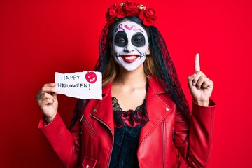 Poster - Woman wearing day of the dead costume holding happy halloween paper surprised with an idea or question pointing finger with happy face, number one