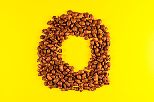 Latin alphabet letters made with coffee beans on yellow background