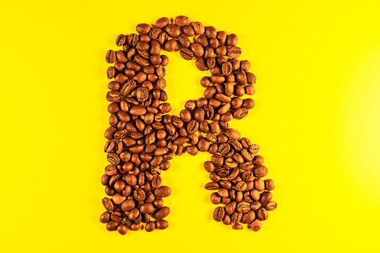 Latin alphabet letters made with coffee beans on yellow background