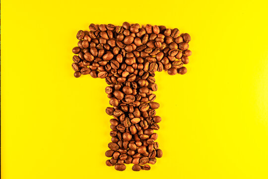 Latin alphabet letters made with coffee beans on yellow background
