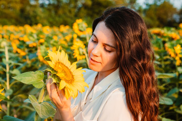 Wall Mural - young beautiful woman at sunflowers field on sunset