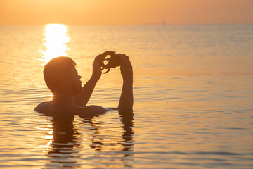 Wall Mural - young man swimming in sea at sunset