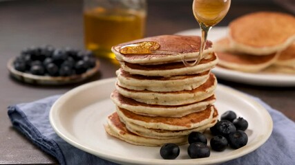 Wall Mural - Honey pouring on pancakes. Whole grain pancakes served with blueberries and raw honey. Sweet breakfast food