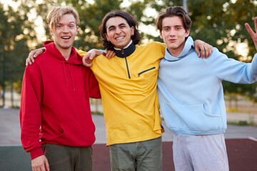 positive smiling young boys look at camera outdoors, they came at sport playground to play basketball, posing