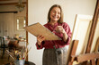 © shurkin_son - Portrait of attractive talented cheerful female pensioner spending retirement enjoying hobby, painting picture at art class, standing in front of easel with paintbrush and palette, smiling broadly