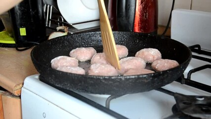 Wall Mural - cooking burger patties in a pan with butter. woman fries meatballs in oil on a hot pan. girl is cooking at home. quarantined food. Recipes and cooking. meatballs for burger meat cutlets in the kitchen