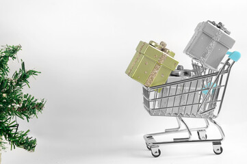 Gift boxes in silvery colors in a basket on a light gray background. The concept of shopping and sales in the winter holidays. Copy space. Selective focus