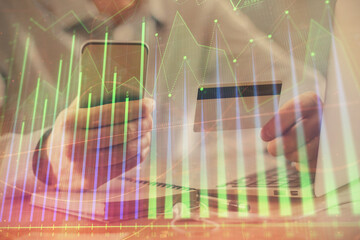 Double exposure of man hands holding a credit card and Forex graph drawing. Stock trading and digital fintech in Internet E-commerce concept.