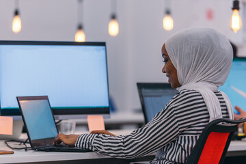 Close-up portrait from the back of a young woman with a white hijab working and typing on her computer