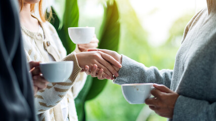 Canvas Print - Closeup image of two people holding hands while drinking coffee together