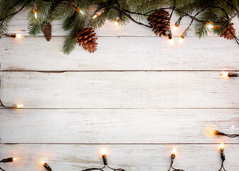 christmas background - christmas lights bulb and pine leaves decoration on white wood plank, frame b