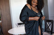 © Roman - good-looking black woman wearing silk dressing gown at home, attractive female has pretty sexy plus size figure. indoors